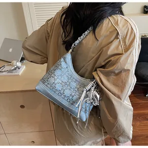 Detail of blue denim crossbody bag with sparkling rhinestones and heart pendant chain