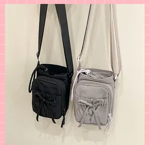 Vue détaillée de sacs bandoulière en nylon avec fermeture à cordon et nœuds décoratifs