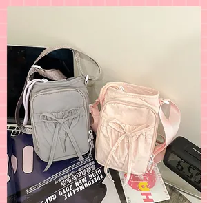 Deux sacs bandoulière en nylon avec cordon nœud et poche zippée sur un bureau de style