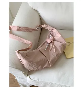 Detail der rosa Nylon-Schultertasche mit Knotenriemen und Herzanhänger-Dekor