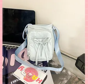 Détail du sac en nylon bleu clair avec nœud décoratif et poche avant zippée