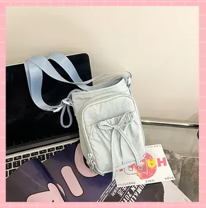 Détail du sac bandoulière bleu clair en nylon avec cordon nœud et double fermeture