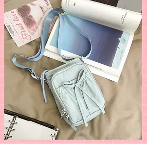Détail d'un sac bandoulière bleu clair avec nœud coulissant et nylon texturé