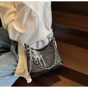 Detail of blue denim hobo bag with silver star charm and chain strap on shoulder