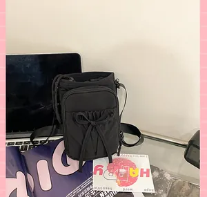 Détail du sac bandoulière en nylon noir avec cordon de serrage et poche zippée latérale