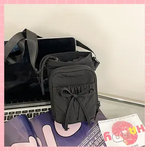 Détail du sac à bandoulière en nylon noir avec poche zippée à nœud et cordon de serrage