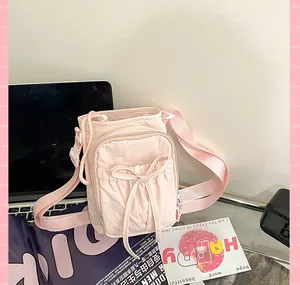 Détail du sac bandoulière en nylon rose clair avec nœud et sangle réglable