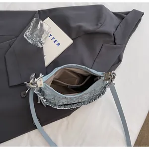 Detail of blue denim jacquard hobo bag showing silver metal chain and logo charms