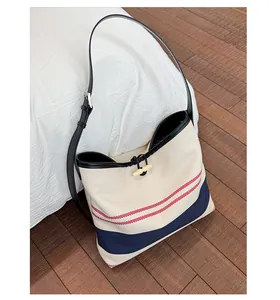 Detail of canvas tote with nautical stripes, leather trim and toggle closure