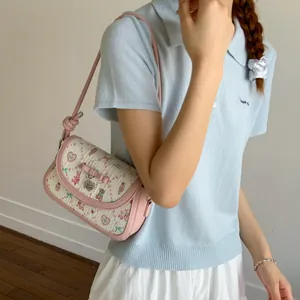 Floral print crossbody bag with pink bow and heart pendant on a female model