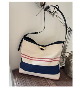 Detail of canvas bucket bag with nautical stripes, toggle closure and black leather trim