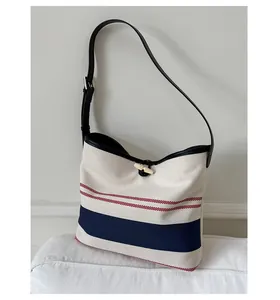 Detail showing nautically inspired striped canvas texture and elegant black leather toggle closure