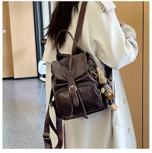 Detail eines dunkelbraunen Lederrucksacks mit Klappschnalle und süßem Kaninchenanhänger