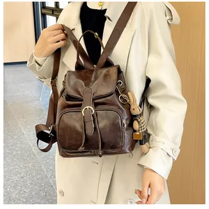 Detail eines dunkelbraunen Kunstleder-Rucksacks mit Schnallenverschluss und Hasenanhänger