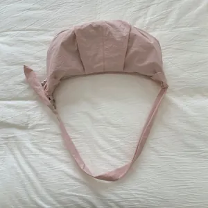 Detailansicht der hellrosa Nylon-Halbmondtasche mit Texturfalten und Knotendetail am Gurt