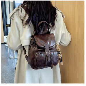 Detail eines dunkelbraunen Vintage-Rucksacks mit Klappschnalle und Hasen-Anhänger