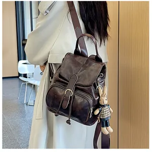 Detail eines dunkelbraunen Vintage-Rucksacks mit Klappe, Reißverschlüssen und Hasenanhänger