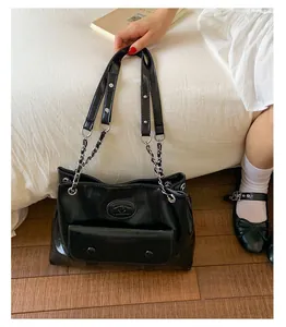 Detail of black glossy leather bag with metal chain strap and front buckle pocket