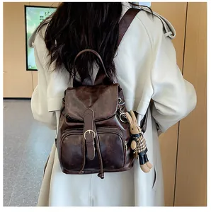 Detail eines dunkelbraunen Kunstleder-Rucksacks mit Klappverschluss und Hasenanhänger
