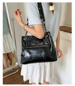 On-body view of black vintage shoulder bag with embossed logo and chain strap