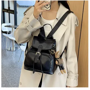 Detail eines schwarzen Klappenrucksacks aus Kunstleder am Model mit Hasen-Anhänger