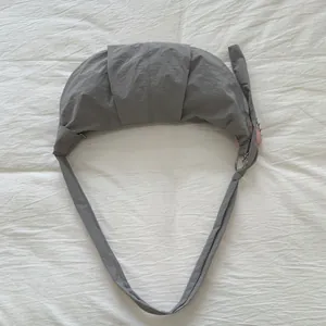 Detail der grauen Nylon-Hobo-Tasche mit Faltenstruktur und rosa Plüsch-Anhänger