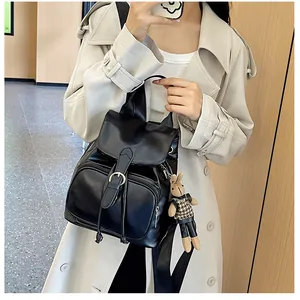 Detail eines schwarzen PU-Lederrucksacks mit Klappe und süßem Kaninchen-Plüschanhänger