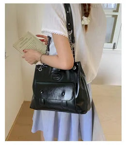 Chic black faux leather tote bag with silver chain strap shown worn on a model's shoulder