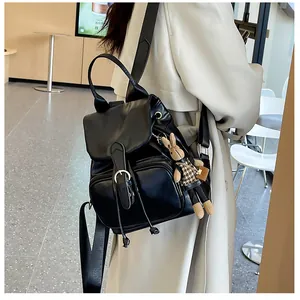 Details des schwarzen Lederrucksacks mit Klappverschluss und süßem Kaninchenanhänger