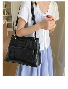 Detail of black glossy shoulder bag with chain strap and vintage double buckle pocket