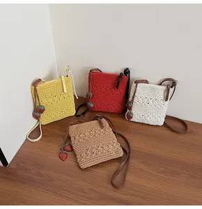 Detailed view of handmade crochet crossbody bags with floral patterns and strawberry charms