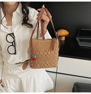 Detail of woven brown shoulder bag featuring intricate floral texture and strawberry charms