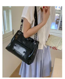 Detail of black glossy leather tote bag with chain strap and kangaroo embossed logo