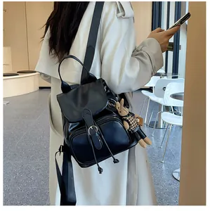 Detail eines schwarzen Rucksacks mit Metallschnalle und süßem Kaninchen-Anhänger-Zubehör