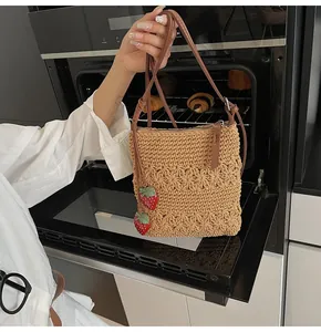 Detail of hand-woven crochet bag with 3D floral patterns and red strawberry charms