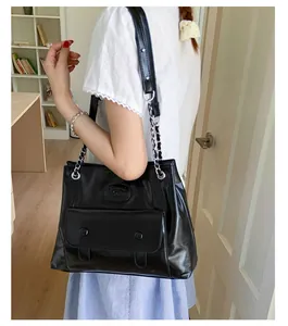 Close-up of black PU leather shoulder bag with chain strap and vintage front pocket detail