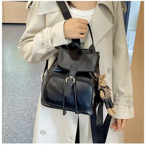 Detail eines schwarzen Lederrucksacks mit Klappe und Kaninchenanhänger am Model