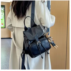 Detail eines schwarzen Klappenrucksacks aus Kunstleder mit niedlichem Hasenanhänger am Rücken