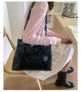 Detail of black vintage faux leather tote with chain strap and front pocket