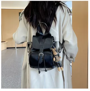 Details eines schwarzen Lederrucksacks mit Klappverschluss und süßem Kaninchenanhänger