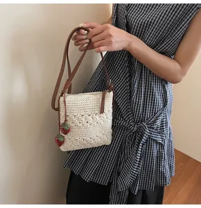 Detail of crochet crossbody bag with floral texture and red strawberry charms