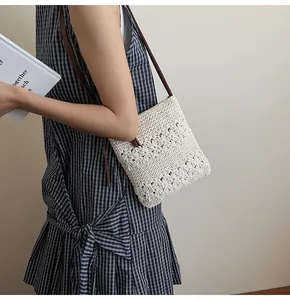 Detail of hollow floral crochet bag in cream white with a slim brown leather strap