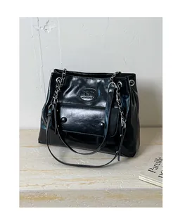 Macro detail of black glossy PU leather handbag with elegant chain strap and logo