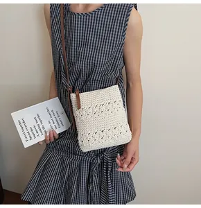 Detail of handmade cream crochet crossbody bag with floral cutouts and leather strap