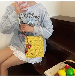 Detailed handmade yellow crochet bag with hollow floral pattern and strawberry pendants