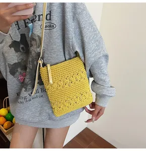 Close-up of yellow crochet crossbody bag with floral cut-out texture and leather strap