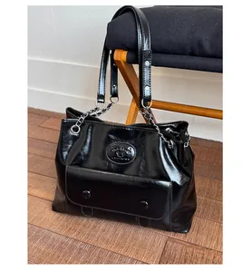 Detail of a black glossy tote bag with double buckle pocket and silver chain straps