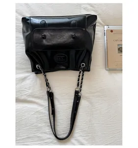 Detail of vintage black PU leather tote bag with silver chain strap and front flap pocket
