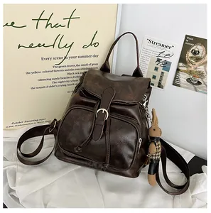 Detail eines braunen Vintage-Rucksacks mit Schnallenriemen und kleinem Hasenanhänger