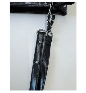 Detail of black glossy shoulder bag featuring silver metal chain and rivet strap accents